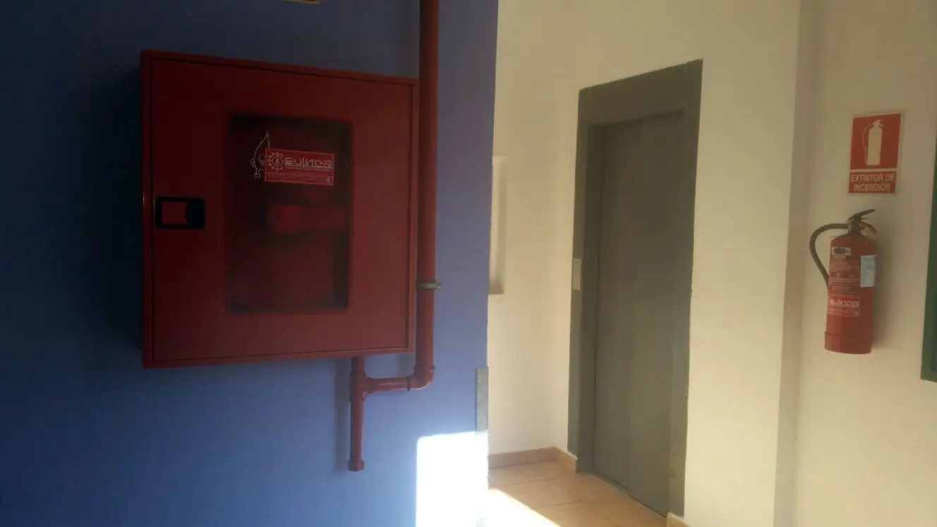 Ascensor adaptado en el pasillo, junto a boca de incendios y extintor