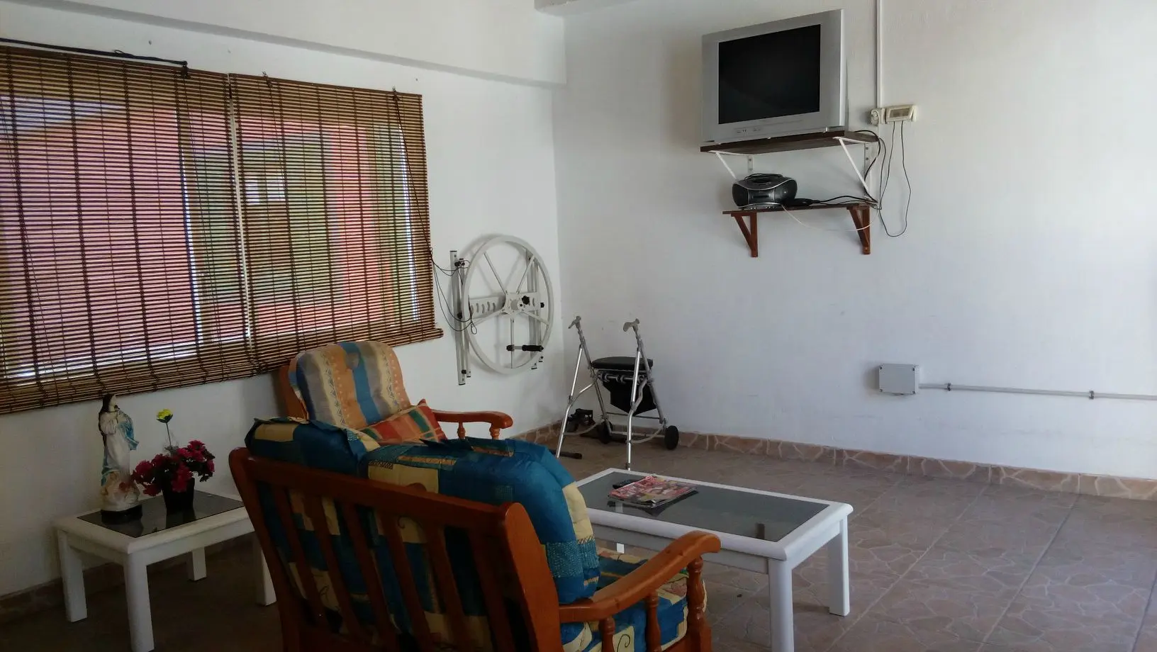 Sala de estar con televisión, sillones y andador a disposición de los residentes